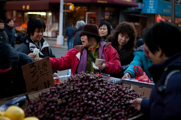 A lady in China Town, New York brokers deals with customers at her fruit stand.  Joseph Amandola III © 2015